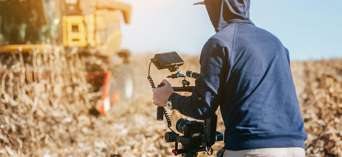 Ag Student holding a video camera filming a combine